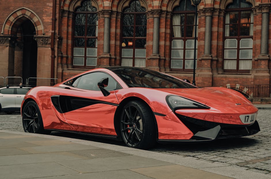 A sleek red sports car parked on a cobblestone city street in front of a historic building.