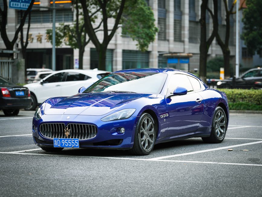 Blue Maserati sports car parked in an urban setting with trees and buildings.