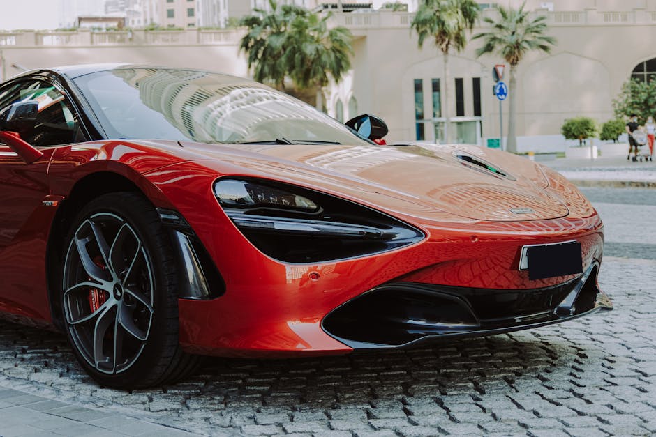 A sleek red luxury sports car parked in downtown Dubai, showcasing modern design and high-end automotive elegance.